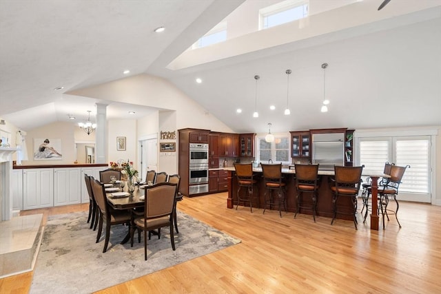 dining area featuring a chandelier, high vaulted ceiling, and light hardwood / wood-style flooring