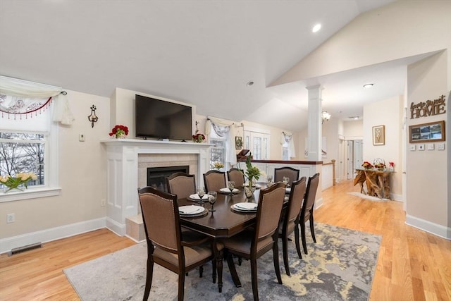 dining space featuring vaulted ceiling, a healthy amount of sunlight, and light hardwood / wood-style flooring