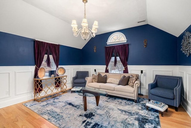 living room featuring hardwood / wood-style flooring, lofted ceiling, and a chandelier