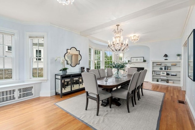 dining room featuring a healthy amount of sunlight, visible vents, an inviting chandelier, and wood finished floors
