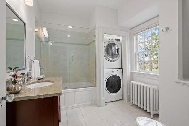 bathroom with radiator, vanity, enclosed tub / shower combo, tile patterned floors, and stacked washer / drying machine