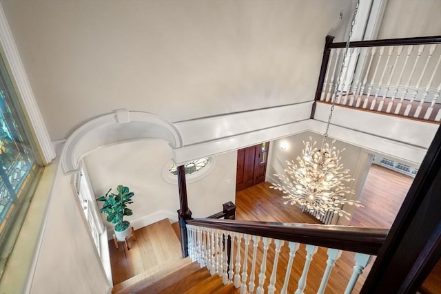 staircase with wood finished floors, a notable chandelier, and visible vents