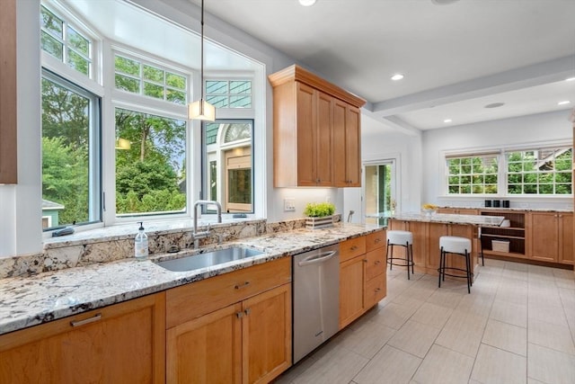 kitchen with light stone countertops, dishwasher, and a sink