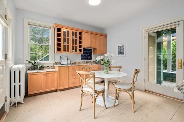 kitchen with glass insert cabinets, open shelves, radiator, and light stone countertops