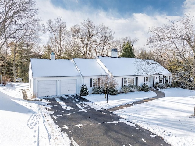 ranch-style home featuring a garage, driveway, and a chimney