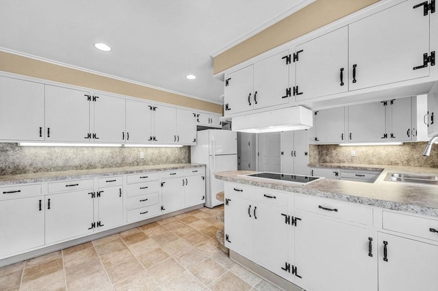 kitchen featuring white cabinets, freestanding refrigerator, black electric cooktop, light countertops, and a sink