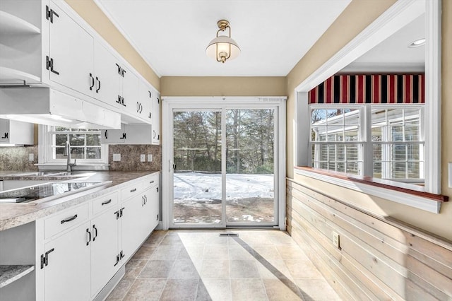 kitchen with black electric cooktop, white cabinetry, open shelves, and a wealth of natural light