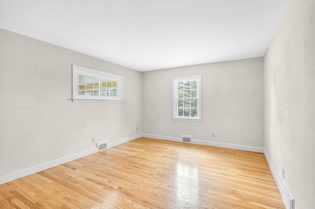 unfurnished room featuring visible vents, light wood-style flooring, and baseboards