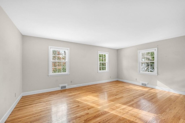 unfurnished room with light wood-style floors, visible vents, and baseboards