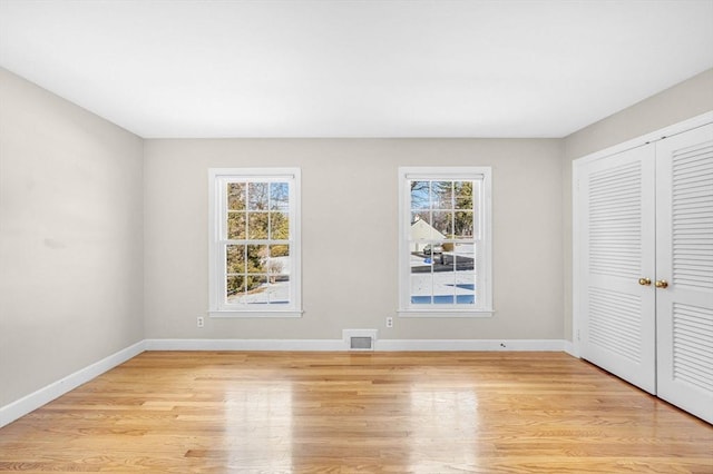 unfurnished bedroom featuring baseboards, a closet, visible vents, and light wood-style floors