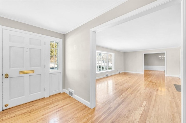 foyer entrance with light wood finished floors, baseboards, visible vents, and ornamental molding