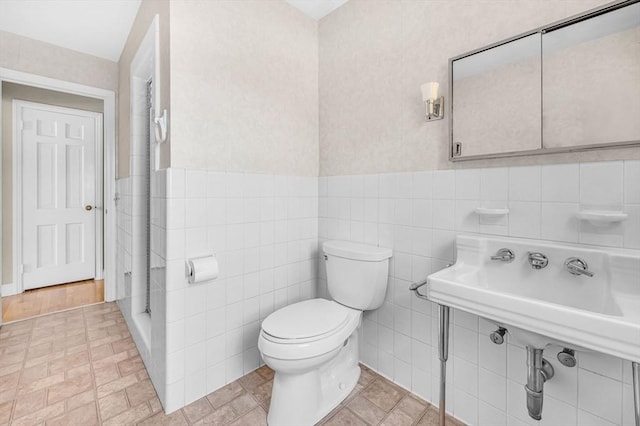 bathroom with toilet, wainscoting, and tile walls