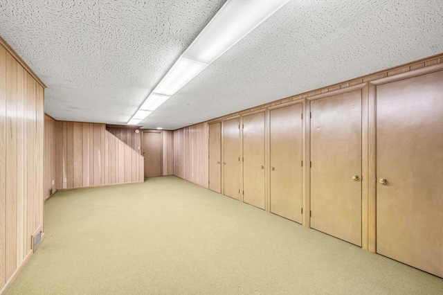 finished below grade area featuring wood walls, visible vents, and light colored carpet