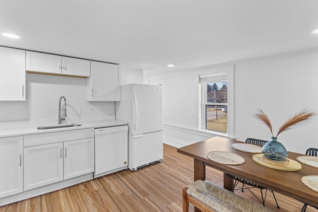 kitchen with white cabinetry, sink, white appliances, and light wood-type flooring