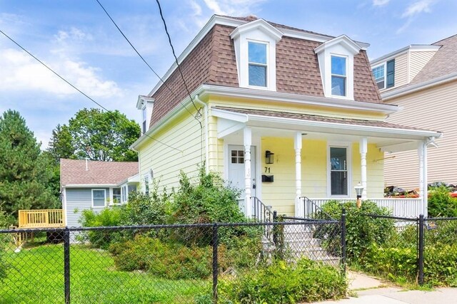victorian home featuring a front yard, mansard roof, a porch, a fenced front yard, and roof with shingles