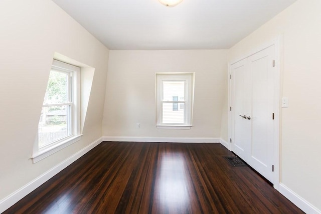unfurnished room featuring dark wood-style flooring, baseboards, and visible vents