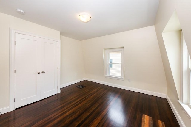 unfurnished room featuring dark wood-type flooring, baseboards, and visible vents