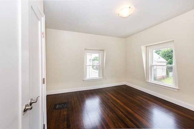 empty room featuring dark wood-type flooring, baseboards, and a healthy amount of sunlight
