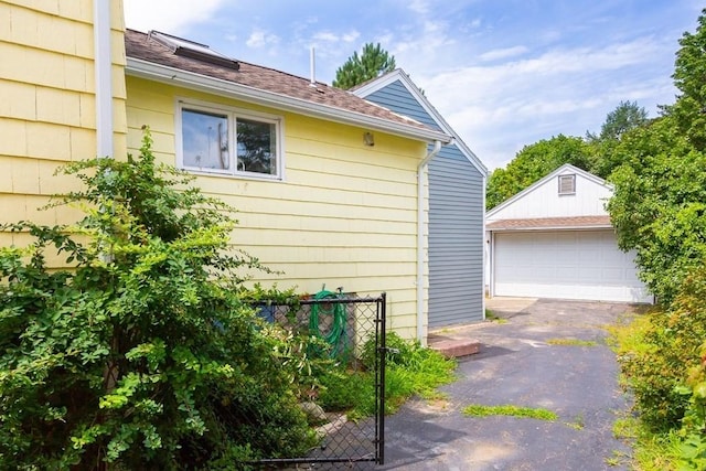 view of side of home with an outbuilding, a detached garage, and fence