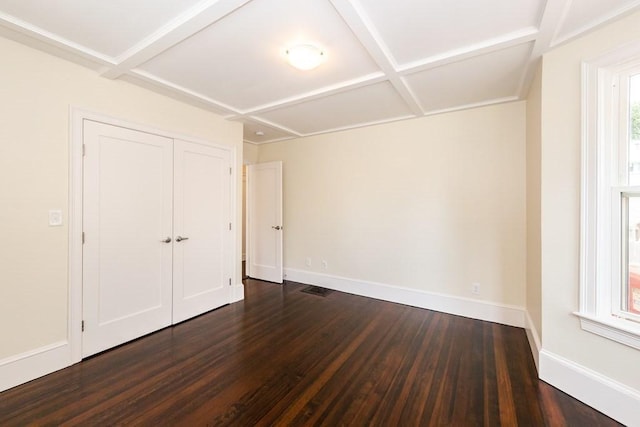 unfurnished bedroom featuring coffered ceiling, a closet, baseboards, and dark wood finished floors