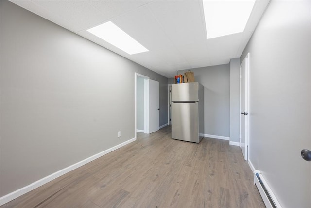 318 Newton St, South Hadley, MA 01075 - empty room featuring light wood-type flooring, a baseboard radiator, baseboards, and a paneled ceiling