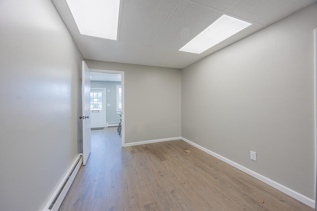 318 Newton St, South Hadley, MA 01075 - empty room featuring baseboard heating, a baseboard heating unit, a skylight, wood finished floors, and baseboards