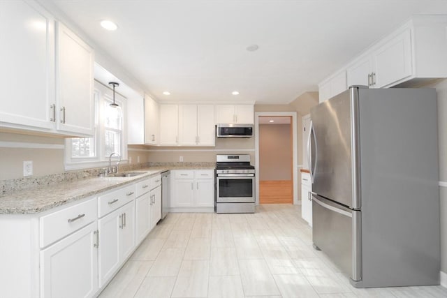 kitchen with a sink, light stone counters, recessed lighting, appliances with stainless steel finishes, and white cabinets