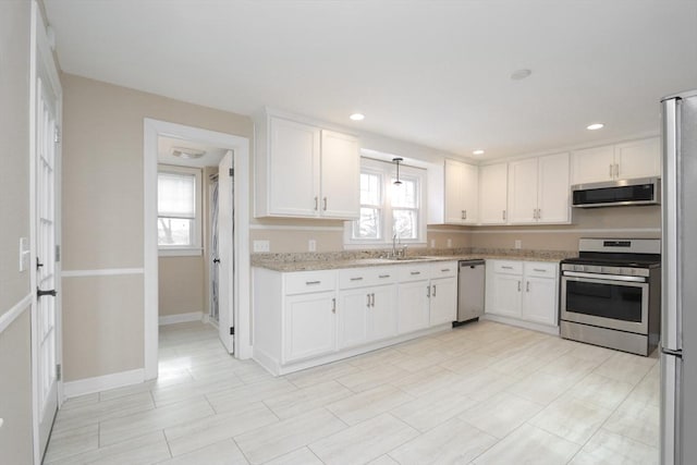 kitchen featuring white cabinets, light stone counters, a healthy amount of sunlight, and stainless steel appliances