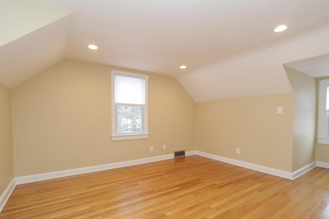 additional living space featuring visible vents, recessed lighting, light wood finished floors, baseboards, and vaulted ceiling