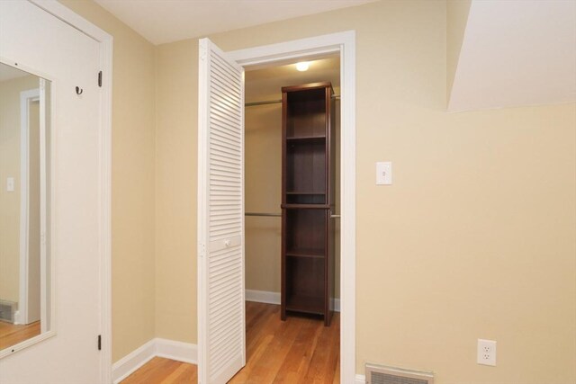 hallway featuring light wood-style floors, visible vents, and baseboards