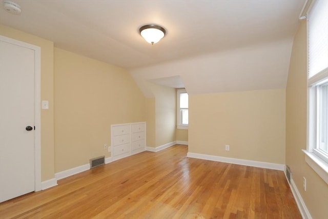 bonus room with vaulted ceiling, light wood-style floors, baseboards, and visible vents