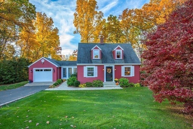 cape cod home with a garage, a front lawn, a chimney, and driveway