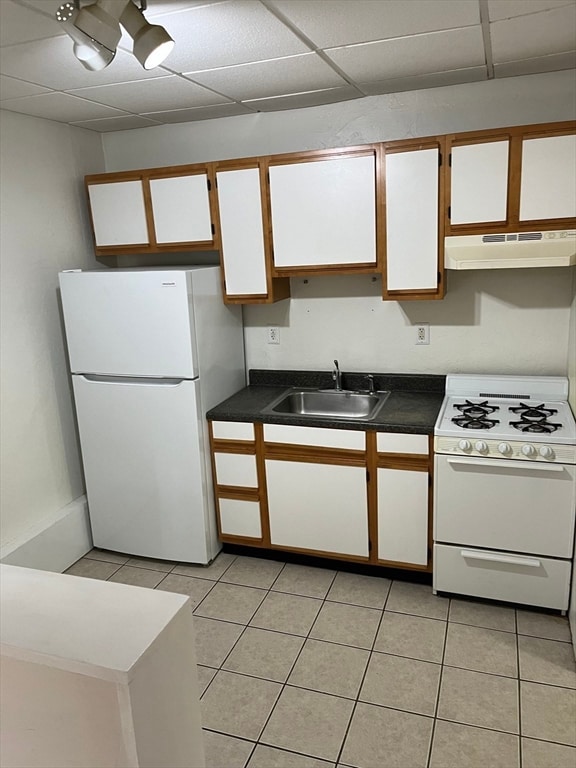 kitchen featuring a paneled ceiling, white appliances, white cabinets, sink, and light tile patterned floors