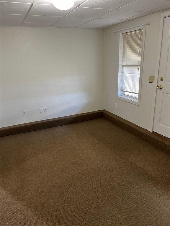 carpeted empty room featuring a drop ceiling