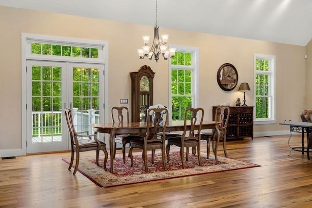 dining area with baseboards, an inviting chandelier, french doors, and hardwood / wood-style floors