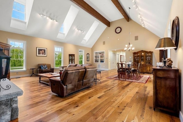 living area with a notable chandelier, light wood-type flooring, a skylight, and plenty of natural light