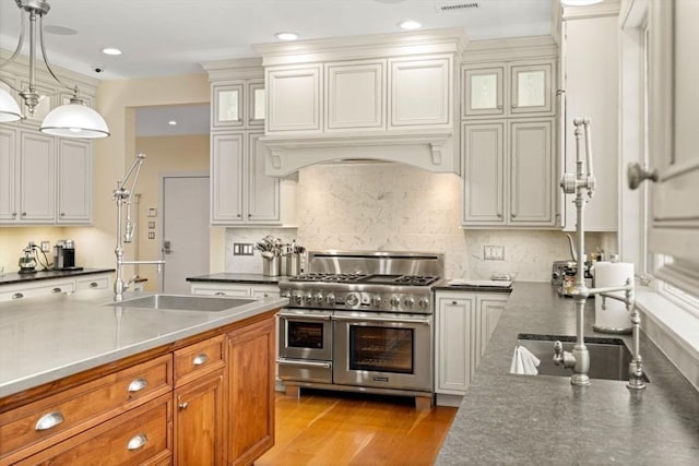 kitchen featuring premium range hood, range with two ovens, dark countertops, and light wood-style floors