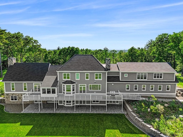 back of property featuring a chimney, a yard, and a patio area