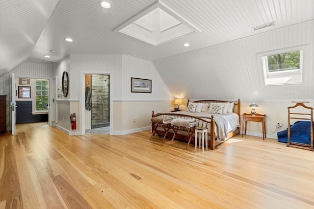 bedroom featuring baseboards, visible vents, wood finished floors, and lofted ceiling with skylight