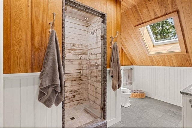 bathroom featuring a shower stall, toilet, a skylight, and wood walls