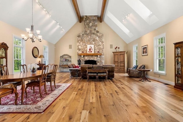 dining area with an inviting chandelier, light wood-style flooring, a skylight, and a healthy amount of sunlight