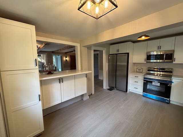 kitchen featuring tasteful backsplash, white cabinets, appliances with stainless steel finishes, and hardwood / wood-style floors