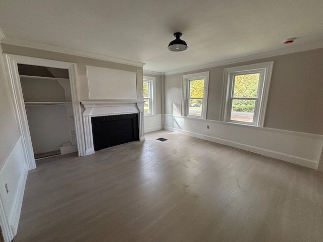 unfurnished living room featuring ornamental molding, light hardwood / wood-style flooring, and a wealth of natural light