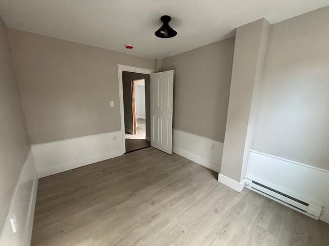 unfurnished room with light wood-type flooring and a baseboard radiator