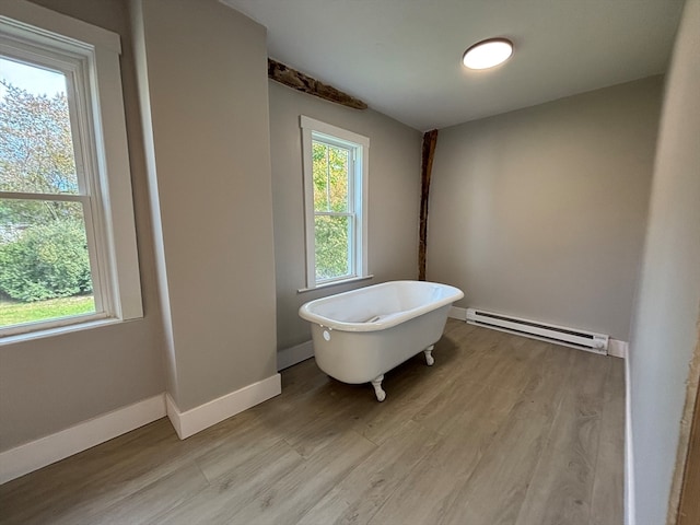 bathroom featuring a bath, wood-type flooring, and baseboard heating