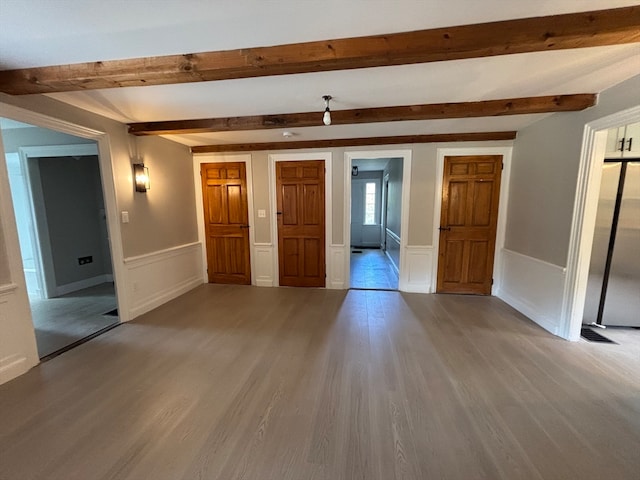 spare room with beamed ceiling and light hardwood / wood-style floors