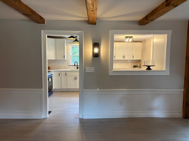 interior space featuring beamed ceiling, sink, and light hardwood / wood-style floors