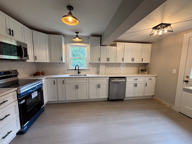 kitchen with appliances with stainless steel finishes, tasteful backsplash, sink, and white cabinets