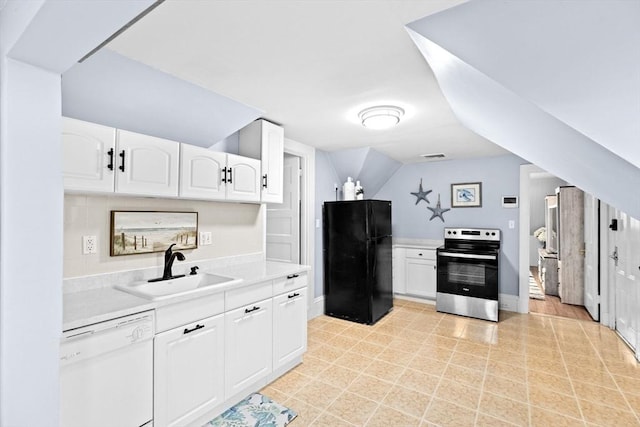 kitchen with white cabinets, a sink, dishwasher, stainless steel range with electric stovetop, and freestanding refrigerator