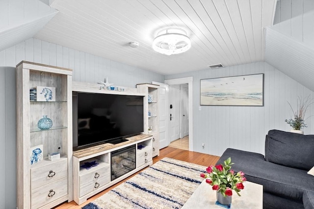 living area with wood walls, light wood finished floors, lofted ceiling, and wood ceiling